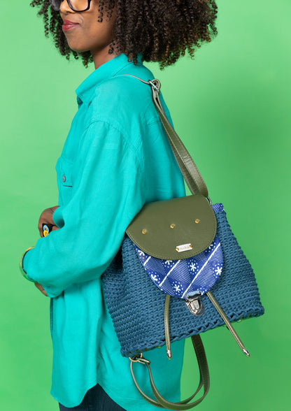 crocheted, dark blue and forest green bag, with an African style print. Model wearing the bag over the shoulder.