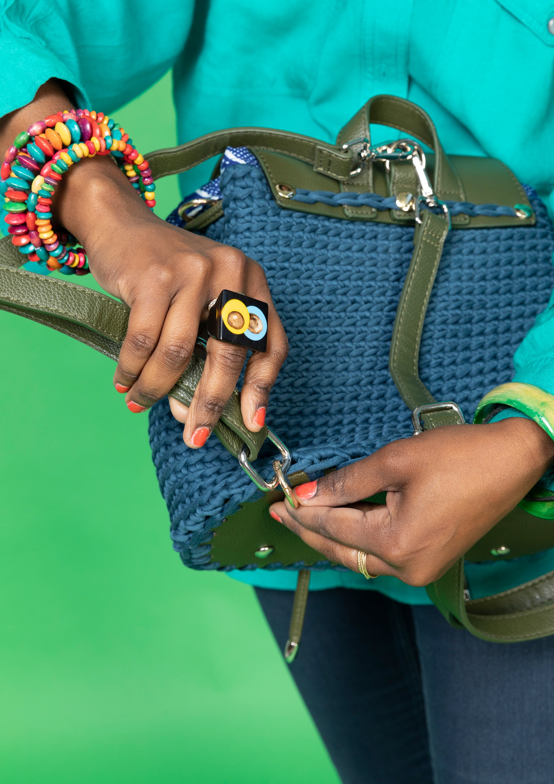 crocheted, dark blue and forest green bag, with an African style print. Model shown adjusting straps.