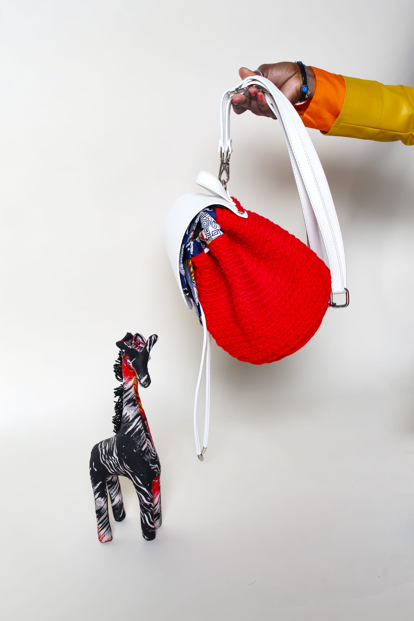 crocheted, red and white bag, with an African style, heart pattern print. held up by straps.  