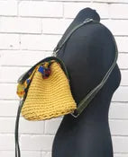 crocheted, golden-yellow and forest green bag, with an African style print. shown on a mannequin, side view. 